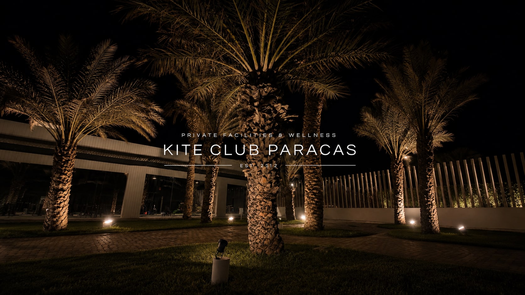 Kite Club Paracas — Private Facilities & Wellness, Est. 2012. Palmeras iluminadas de noche junto al gimnasio del club